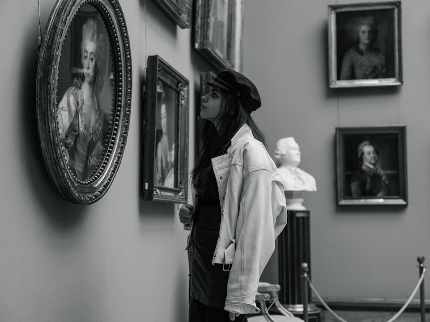 Black and white photo of a person admiring paintings in a museum gallery