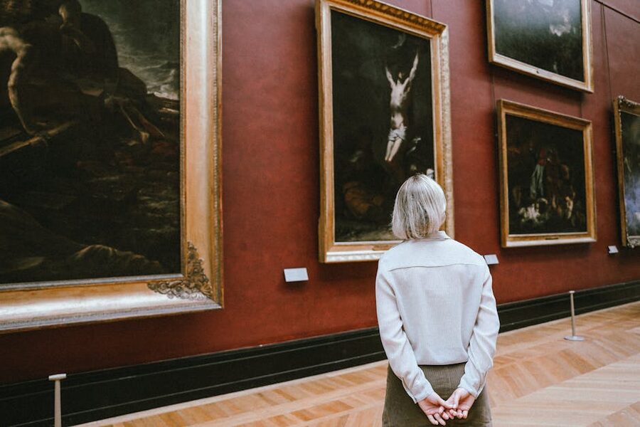 A woman observing paintings in a museum