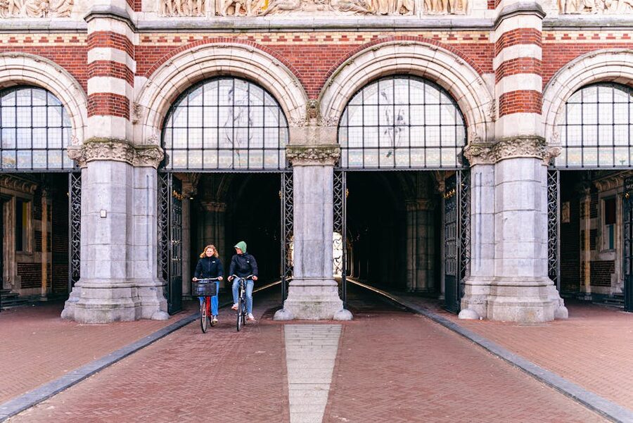 Two cyclists riding through the Rijksmuseum archway