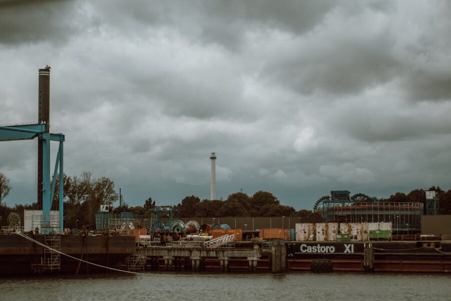 The Castoro XI heavy-lift barge moored in the Port of Rotterdam with containers and harbour equipment