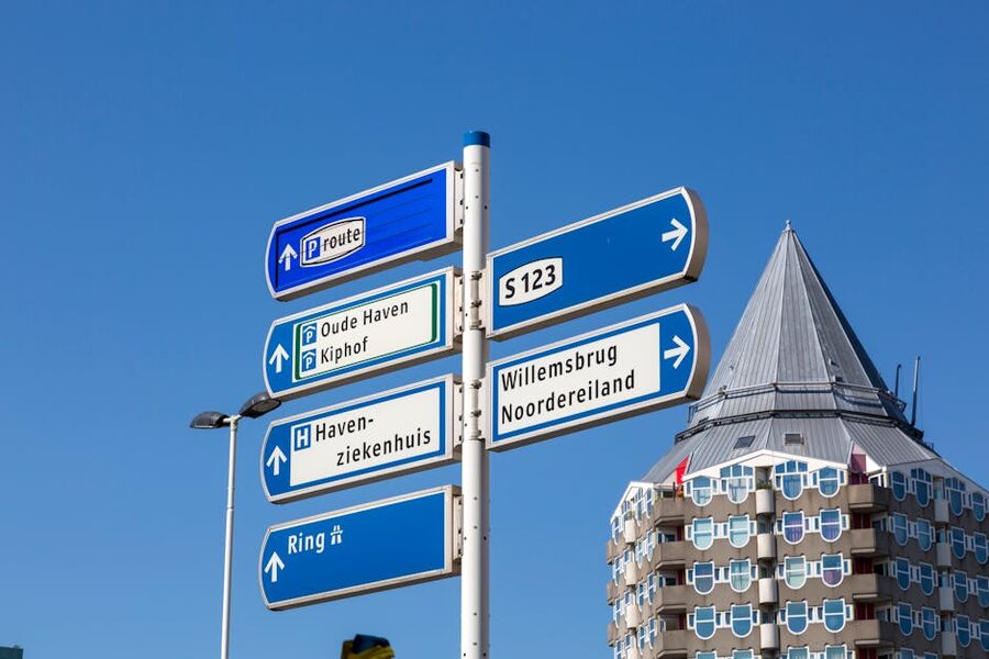 Street signs pointing to the Cube Houses in central Rotterdam under a clear blue sky