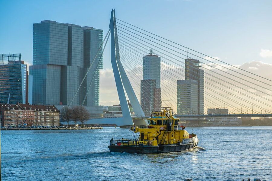The Erasmus Bridge spanning the Maas in Rotterdam with a yellow boat passing underneath