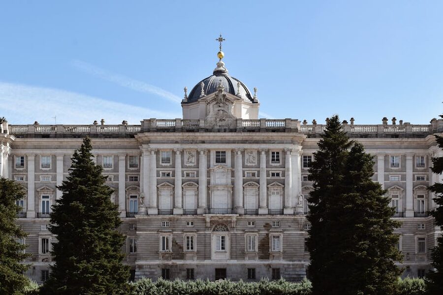 The grand facade of Royal Palace of Madrid framed by trees