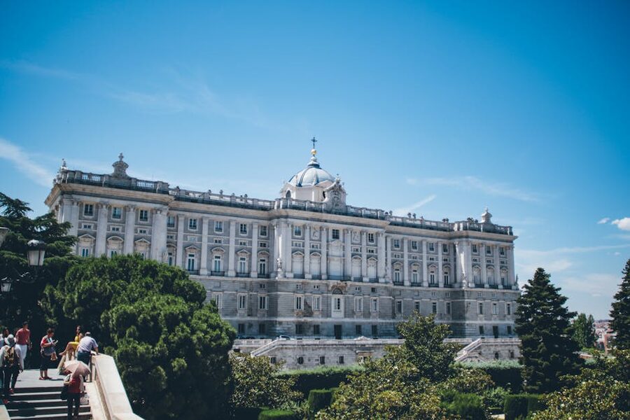 Royal Palace Madrid with greenery and visitors below
