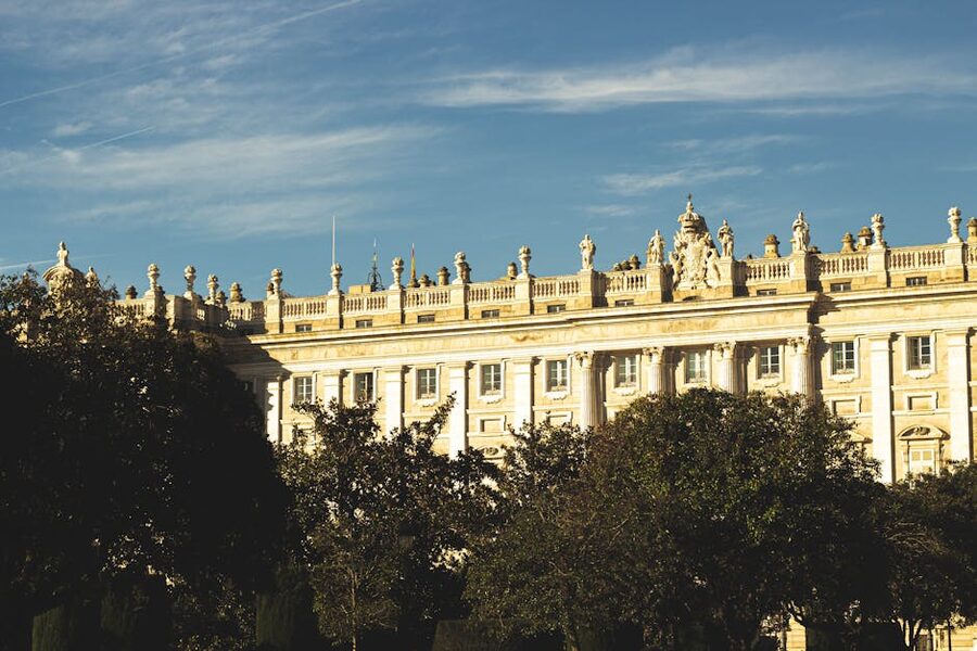 Sunlit facade of Royal Palace Madrid amid lush greenery
