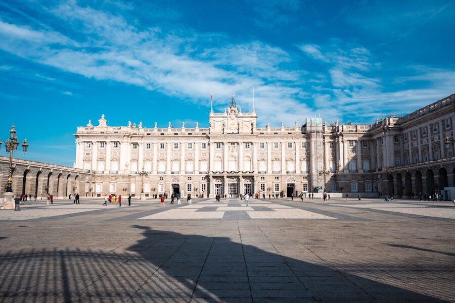 Royal Palace Madrid on a sunny day with visitors in the plaza