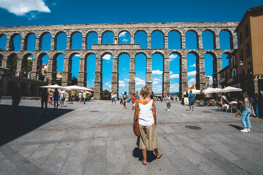 Tourists standing in Plaza del Azoguejo at the base of Segovia aqueduct
