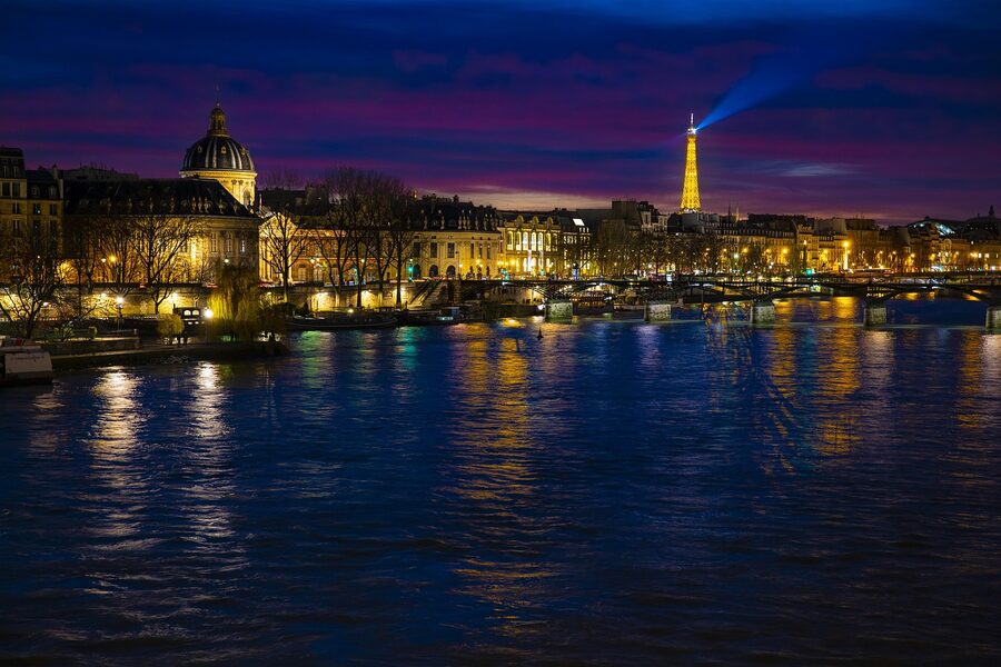 Seine bridges and Paris monuments lit up at night with reflections on the river
