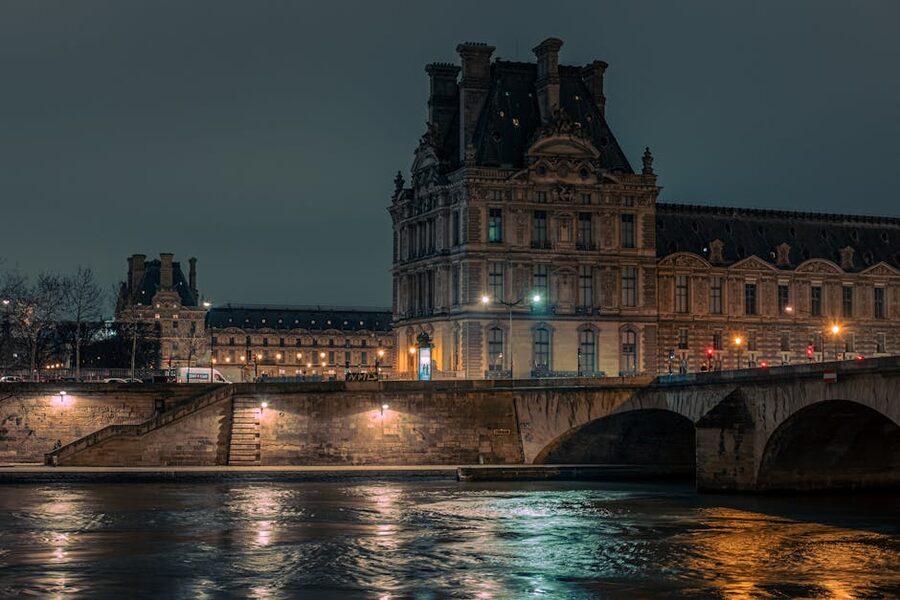 The Louvre Museum illuminated at night seen from the Seine river
