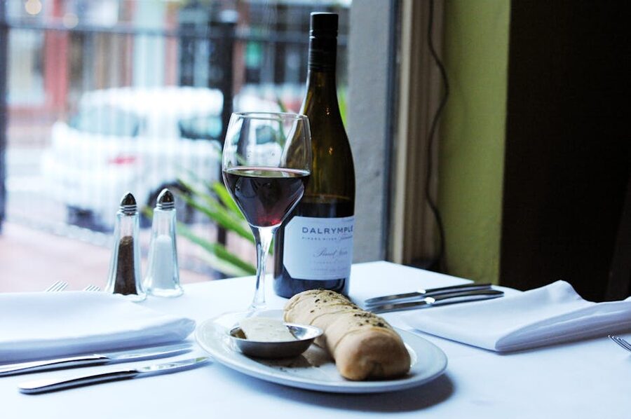 Restaurant table set with wine bread and condiments next to a window