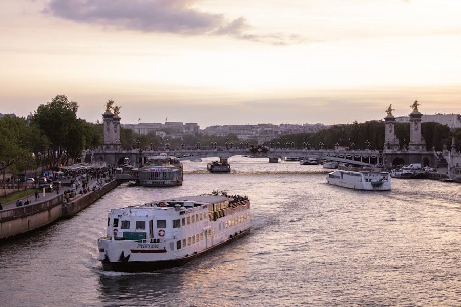 Pont Alexandre III at sunset with cruise boats moored along the Seine quay in Paris
