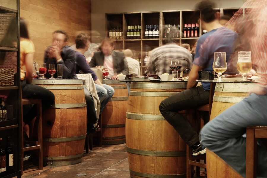 Rustic tapas bar with people sitting around wine barrels