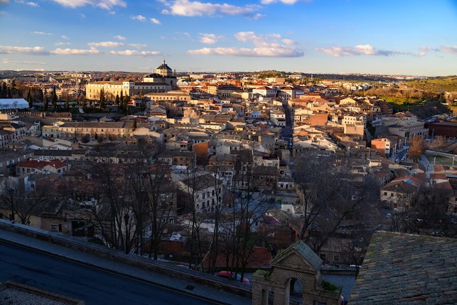 Toledo cityscape at twilight under a clear sky, lights coming on across the medieval old town