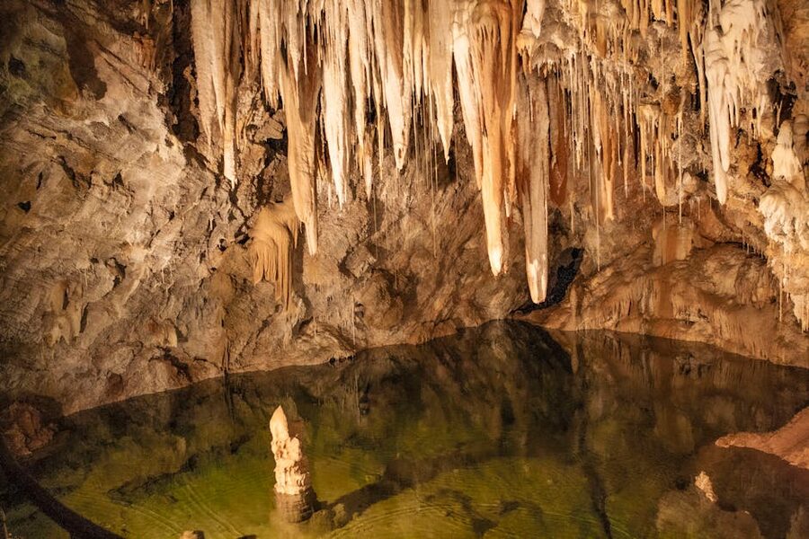 Stalactites and reflective pool inside cave
