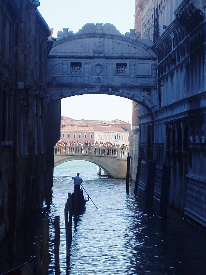 Black gondola passing under the white stone Bridge of Sighs in Venice