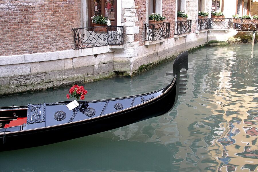 Empty black gondola moored at the edge of a Venetian canal in late afternoon light