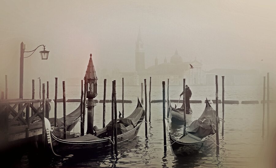 Gondola emerging from morning fog on a Venetian canal