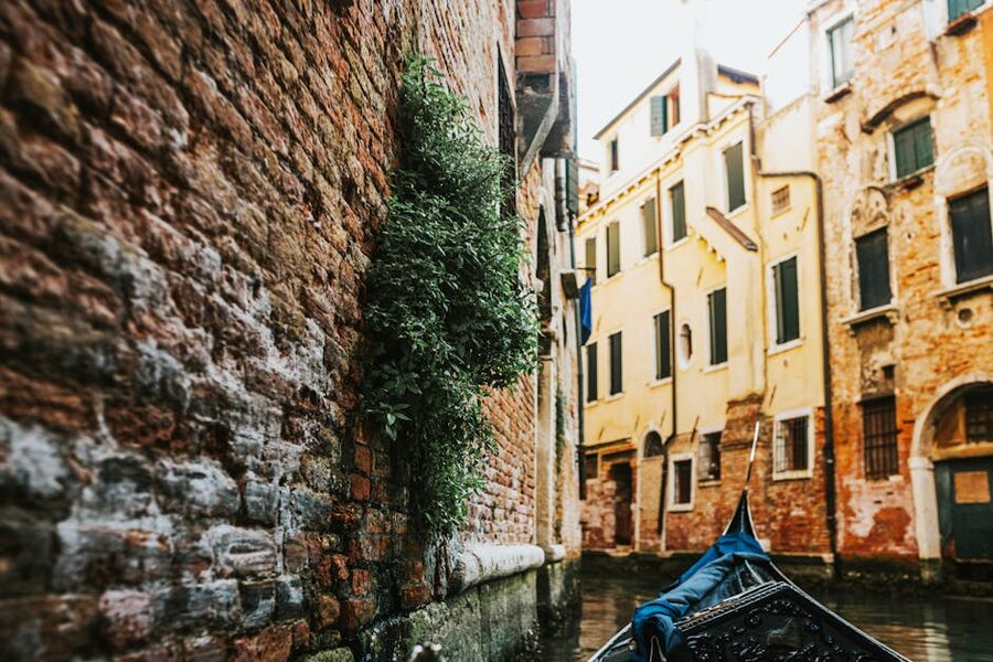 Black gondola passing along a narrow brick-walled side canal in Venice