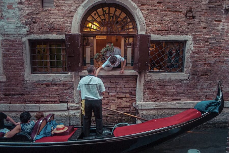 Black gondola gliding past a brick palazzo wall on a quiet Venetian canal