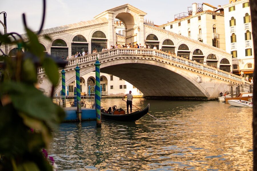 Gondola passing Venice's Rialto Bridge at sunset with golden reflections
