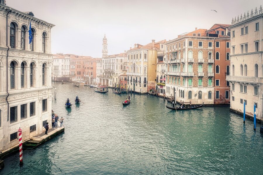 Tourists in a Venetian gondola being rowed through a calm side canal