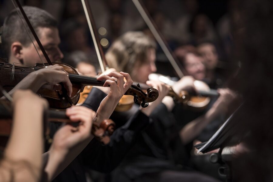 String section of an orchestra with violins and cellos performing