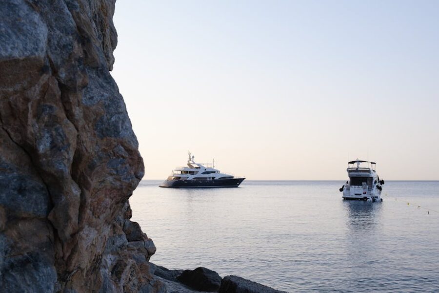Yachts anchored at rocky shore at sunset Mediterranean